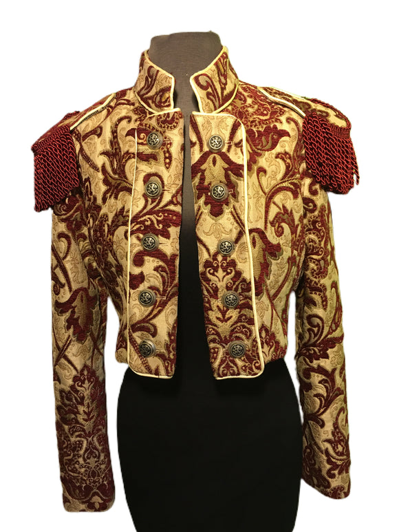 European cut, women’s formal riding jacket. Beautiful short jacket with a stand-up collar made in rich tapestry fabric. Ten medieval lion buttons fasten front lapels which also can be unbuttoned and worn crossing over in double-breasted style. Matching smaller buttons fasten cuffs. Ornate bullion fringe epaulets add an authoritarian vibe. Lined in rich black satin. Wonderful!  