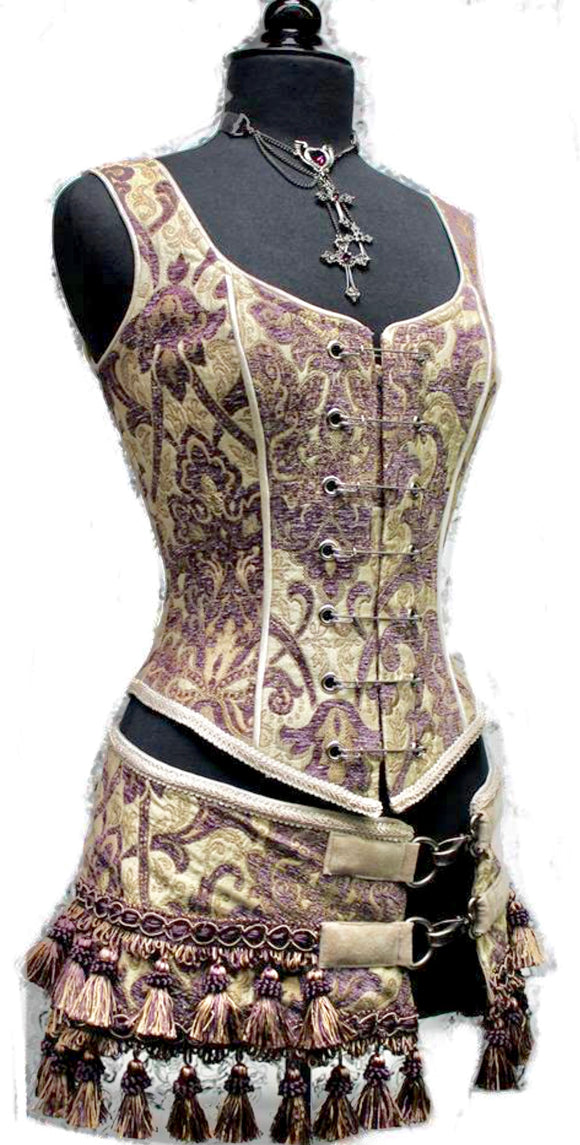 A Shrine classic!! A heavily constructed corset top in rich purple and ivory tapestry fabric with a great form fit. Heavy metal boning at sides and lycra stretch panel at back adds extra strong support. Fastens in front with seven large kilt pins but also zips in back for easy access. Rich ivory satin piping around armholes and neckline and ivory satin lining inside. Trimmed at the bottom with braided trim. 