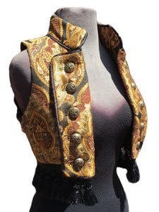 A beautiful pirate/bellydancer/burlesque vest from the old country. A short vest with a stand-up collar in vintage european style, made in rich gold/brown/green/black tapestry fabric with black satin lining inside. Exquisite black satin piping trim all over. Front fastens back with ornate metal medieval lion buttons or can be undone and crossed over worn double-breasted fashion. Elaborate black tassel trim at the bottom. Great for any bohemian affair. Splendid! Measurements: Small: Chest 32_ Ribcage 30_